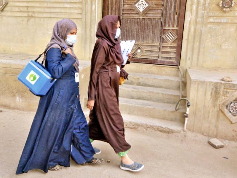 Polio vaccinators, carrying bag of vaccines and documents to collect data, walk through a neighbourhood in Karachi at the start of a nationwide inoculation drive. Photo: Jalal Qureshi/express